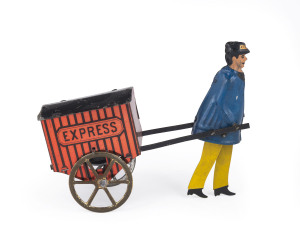LEHMANN "EXPRESS" PORTER, Germany, lithographed tinplate, depicts full figure porter pulling an enclosed cart marked "Express", spoke wheels. Length: 15cm (6"). This is the flywheel version, that acts as a friction mechanism, when the knob is spun it wil