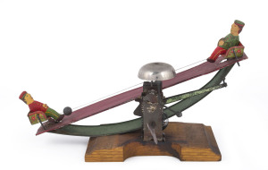 Early painted tin clockwork seesaw toy, with a boy on opposing sides kicking a ball between them; a bell rings to keep them further entertained. Length: 24cm (9.5").