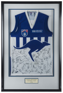 NORTH MELBOURNE: framed and glazed North Melbourne football guernsey signed by members of 1998 team who went on to compete in the Grand Final, numerous signatures including Wayne Carey, Glenn Archer, Byron Pickett, Martin Pike, Mick Martin & Peter Bell; overall 71x108cm.