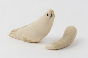 Two whale's teeth, one carved into the form of a seal, mid 20th century, the seal 11cm long