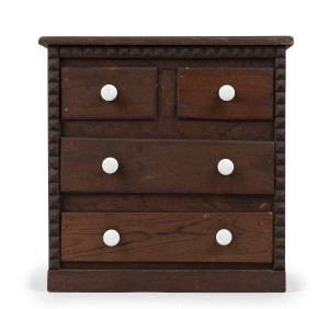 An Australian folk art miniature chest of four drawers, cedar and pine with porcelain knobs, 1890s depression era, 35cm high, 34cm wide, 18cm deep