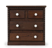 An Australian folk art miniature chest of four drawers, cedar and pine with porcelain knobs, 1890s depression era, 35cm high, 34cm wide, 18cm deep