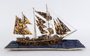 A model tallship made from tortoiseshell resting on a blue silk covered board, late 19th century, the ship 30cm high, 46cm long