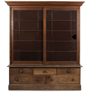 An impressive library bookcase with early astgragal glazed sliding doors above a bank of five staggered drawers, Australian cedar, New South Wales origin, mid 19th century, 227cm high, 193cm wide, 49cm deep