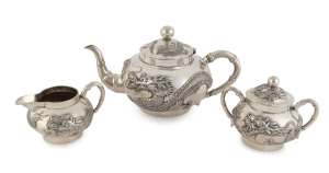 A Chinese silver three piece tea service with engraved and repoussé dragon decoration by Sing Fat of Canton, circa 1900, with presentation inscription to teapot, the teapot 13cm high, 24cm across, 820 grams