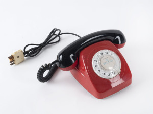 A vintage telephone with rotary dial in two tone red and black plastic, circa 1970s, ​23cm wide