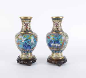 A pair of Chinese cloisonne vases with flying cranes, early to mid 20th century, on carved wooden stands, ​24cm high