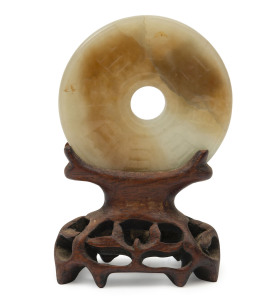 Archaic Chinese jade bi disc with carved designs, on later carved timber stand, 5.5cm diameter
