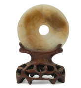Archaic Chinese jade bi disc with carved designs, on later carved timber stand, ​5.5cm diameter