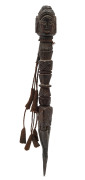 A Tibetan phurba, carved wood with three faces and intricate geometric design, iron tip with silk and cloth tassels, 19th century, 18cm long