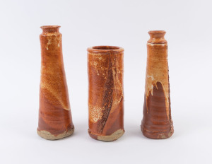 Three tall studio pottery vases with orange glazes, the largest 26cm high