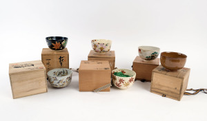 Six assorted Japanese ceramic tea bowls in wooden boxes, the largest 8cm high, 13cm diameter