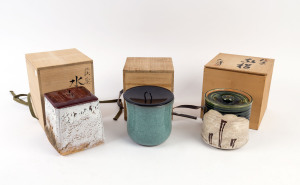 Three Japanese ceramic lidded water jars in wooden boxes, the largest 17cm high
