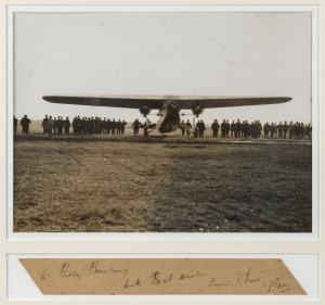 An original albumen photograph of The Southern Cross about to depart from California (22x29cm) mounted, framed & glazed together with a card with the hand-written dedication "To: Billy Beausang, With Best wishes, From "Chas" C.T.P. Ulm, 1928". Overall 48 