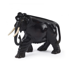 An elephant statue, carved timber with glass eyes and bone tusks, South Asian, 19th century, 18cm high, 23cm long