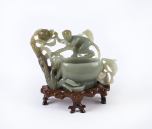 A Chinese carved jade monkey bowl on wooden stand, 20th century, ​13.5cm high, 17cm wide