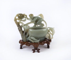 A Chinese carved jade monkey bowl on wooden stand, 20th century, 13.5cm high, 17cm wide
