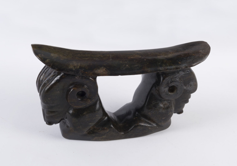 A Chinese headrest pillow, carved nephrite with ram's head decoration, ​13.5cm high, 25.5cm across