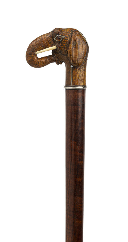 A fine walking stick with elephant head handle covered in snakeskin with glass eyes, ivory tusks and bound in silver; beautiful fiddleback timber shaft with brass and iron ferrule, 19th century, 90cm high