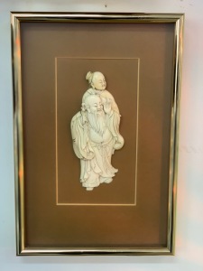 A Japanese carved ivory plaque, Meiji period, 19th century, later mount and framing, the carving 18cm high, frame 36 x 25cm overall