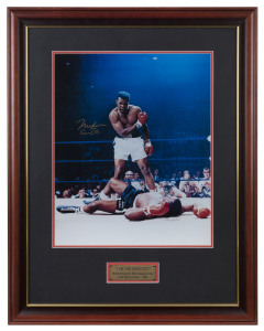 MUHAMMAD ALI: signed colour photograph (49x39cm) of a triumphant Ali standing over a vanquished Sonny Liston, following his 1st round KO of Liston during their May 1965 rematch; framed & glazed, overall 81 x 62.5cm.
