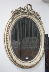 An antique French oval mirror in gilt and lime washed frame with applied floral decoration, 19th century, 83 x 66cm