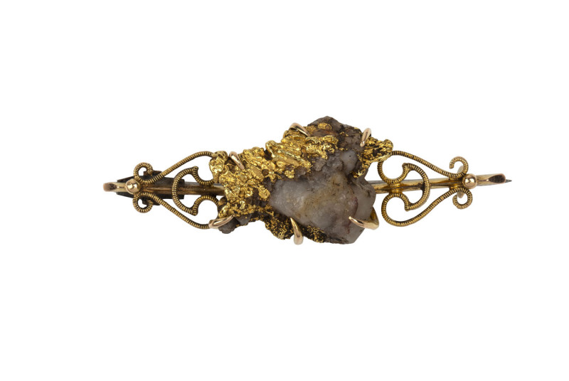 Australian goldfields bar brooch, 18ct gold set with large matrix gold nugget specimen, 19th century, stamped "18c" with two pictorial maker's marks, housed in a C. MARKS & Co of Ballarat plush box. ​5cm long, 10.6 grams