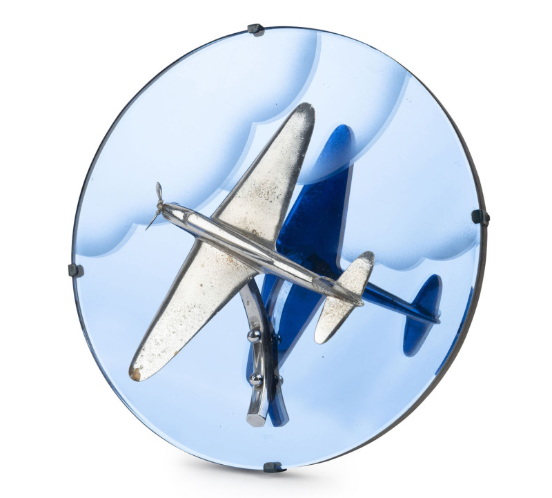 A chrome aeroplane ornament mounted on blue glass circular panel, circa 1940s, 31cm diameter