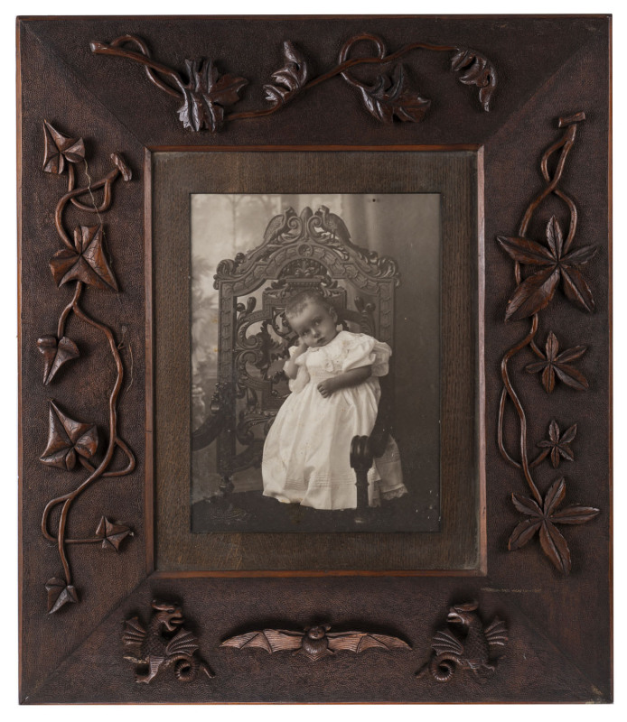 An Australian folk art carved cedar picture frame with a period portrait photograph of a child, circa 1900, 76 x 64cm