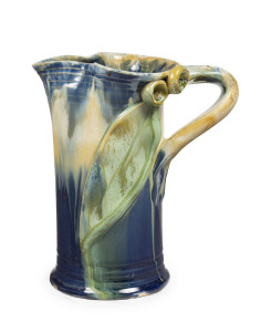 REMUED pottery jug, early shape with applied branch handle, gum nuts and leaf, glazed in blue, cream and green, incised "Remued, 172/6M", ​16cm high