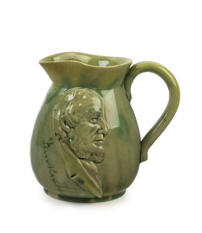 REMUED "FAWKNER" green glazed pottery jug with applied profile portrait of John Fawkner (one of the city of Melbourne's founding fathers), incised "Remued", ​12cm high