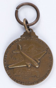 THE LONDON to MELBOURNE, MacROBERTSON CENTENARY AIR RACE 1934 Bronze fob created to honour the winning entry, the "Uiver", 25mm diameter and depicting the aeroplane, a KLM Douglas DC2 in flight over a map depicting the route (obverse); the reverse with "D