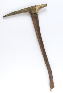 A miner's pick, four pound solid cast brass with later timber handle, ​81cm high