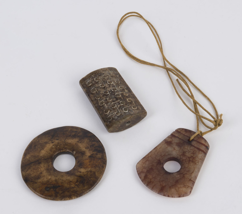 Two Chinese carved jade amulets and a pi disc, the disc 6cm diameter