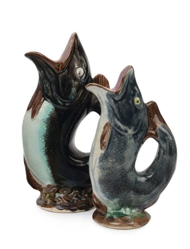 Two antique majolica fish jugs with dark glaze and pink interiors, 19th century, 23cm and 27.5cm high