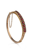 An antique English bangle, 9ct gold set with rubies and diamonds, hallmarked for Sheffield, 19th century, ​housed in original plush fitted leather box, 7cm wide, 7.7 grams total