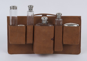 A leather hold all with six English sterling silver topped cut glass bottles, a jar and a brandy flask. Formerly the property of the famed Western Australian gold mining magnate Claude de Bernales who basically kept the State solvent during the Great Depression. This set bearing his monogram was originally housed in his Rolls Royce. 38cm wide