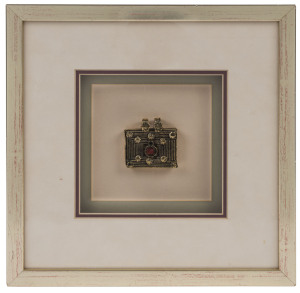 A Tibetan pendant, 19th century, framed and mounted, the pendant 5 x 5cm, frame 26 x 26cm overall