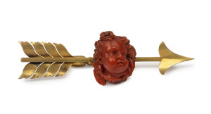 A large antique arrow bar brooch, 15ct yellow gold with ornately carved coral cupid head, 19th century, 9cm long, 23 grams total