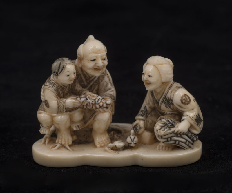 A Japanese carved ivory Okimono of the bird feeders, with coloured staining, Meiji period, 4.5cm high, 6cm wide