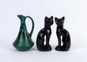 A pair of vintage porcelain cat statues together with a green ceramic jug, mid 20th century, the cats 21cm high