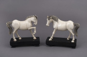 A pair of antique Chinese carved ivory horse statues, late 19th early 20th century, on lacquered stands, ​13cm high, 13cm wide overall