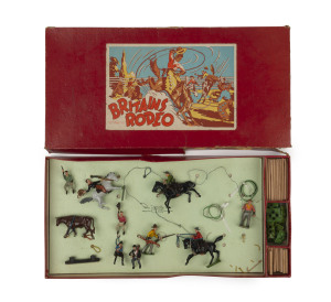 BRITAINS: - Boxed - Rodeo Set: comprising hollow cast lead mounted riders (3, two with lassos), figures on foot (2, one with lasso), seated figures (3) & cow (1), also bases (15) & wooden poles to construct the stockade; appears largely complete ex one ba