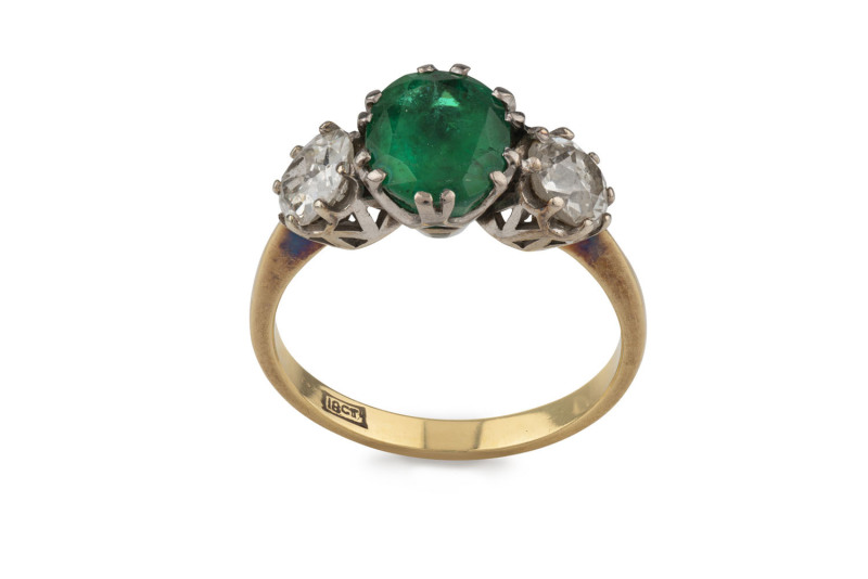 An antique yellow gold ring set with an impressive central emerald flanked by two 0.5ct diamonds set in white gold, early 20th century, ​3 grams total