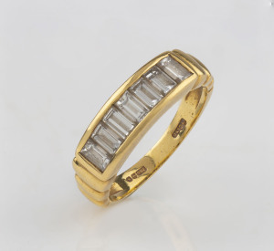 A vintage 18ct yellow gold ring set with a row of seven baguette cut white diamonds, stamped "H.C. Ltd. 750", with pictorial marks, ​3.9 grams total