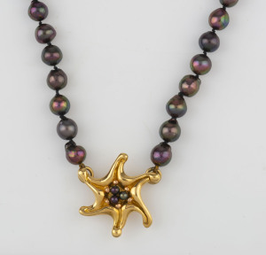 A strand of black pearls with star shaped 18ct yellow gold pendant clasp, ​42cm long