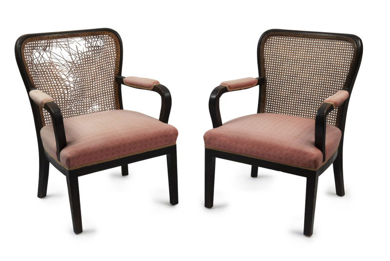 A pair of Austrian Art Deco armchairs, ebonised frames with rattan backs and pink upholstery, ​88cm high, 60cm across the arms