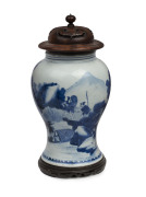 A fine Chinese baluster shaped vase with underglaze blue decoration of fishing figures in landscape, Kangxi Period, circa 1700, with carved hardwood lid and timber stand, 26cm high