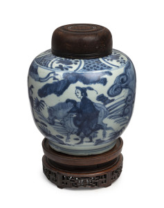 A Chinese ovoid porcelain jar, underglaze blue decoration with figures and donkey in landscape, Ming Dynasty, circa 1500, with accompanying finely carved wooden stand and lid, 23cm high overall