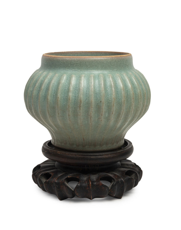 A Chinese Longquan green celadon ribbed vase, Southern Song Dynasty, circa 1300, with later carved wooden stand, the vase 10.5cm high, 13.5cm diameter